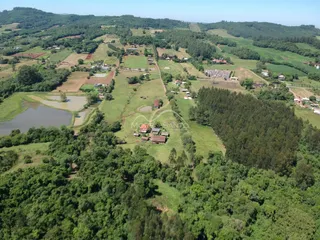 Vista aérea de uma propriedade rural com campos e vegetação densa.