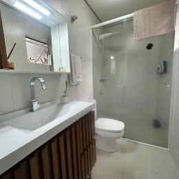 Foto de um banheiro com bancada e box de vidro.