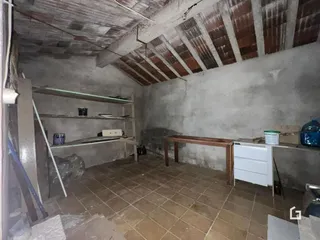 Interior de um cômodo com teto de telhas exposto e piso de cerâmica.