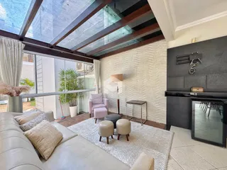 Sala de estar com pé direito alto e grande janela de vidro.