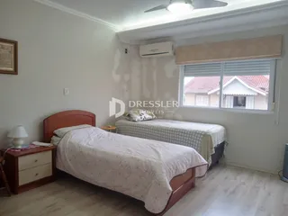 Quarto com duas camas e móveis de madeira clara.