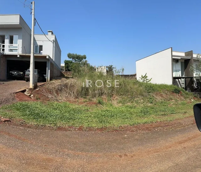 Fachada de duas casas brancas em Lajeado, Brasil, com vegetação alta no terreno.