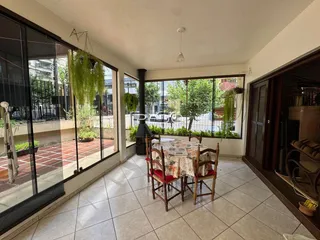 Interior de uma sala com vista para o jardim através de grandes janelas.