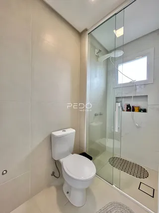 Foto interna de um banheiro com revestimento branco.