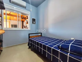 Quarto com cama azul e branca e janela de madeira.