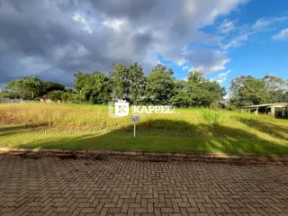 Vista externa de um terreno com grama e árvores ao fundo.