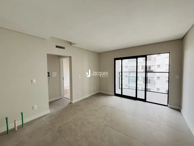 Espaço interno de uma sala com paredes brancas e piso de concreto.