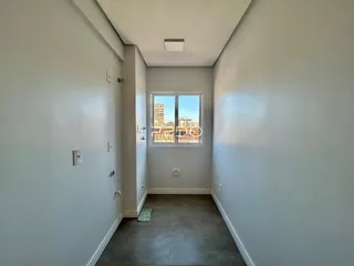 Corredor interno de um imóvel em Lajeado, Brasil, com parede clara e piso de concreto.