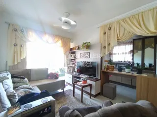 Uma sala de estar interna com janelas e cortinas.