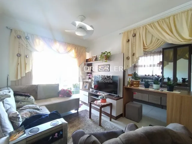 Uma sala de estar interna com janelas e cortinas.