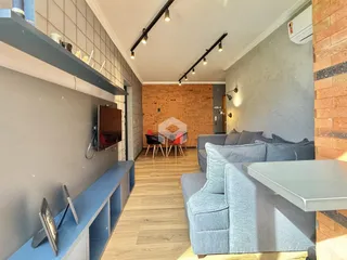 Sala de estar com piso de madeira e parede de tijolos aparentes.