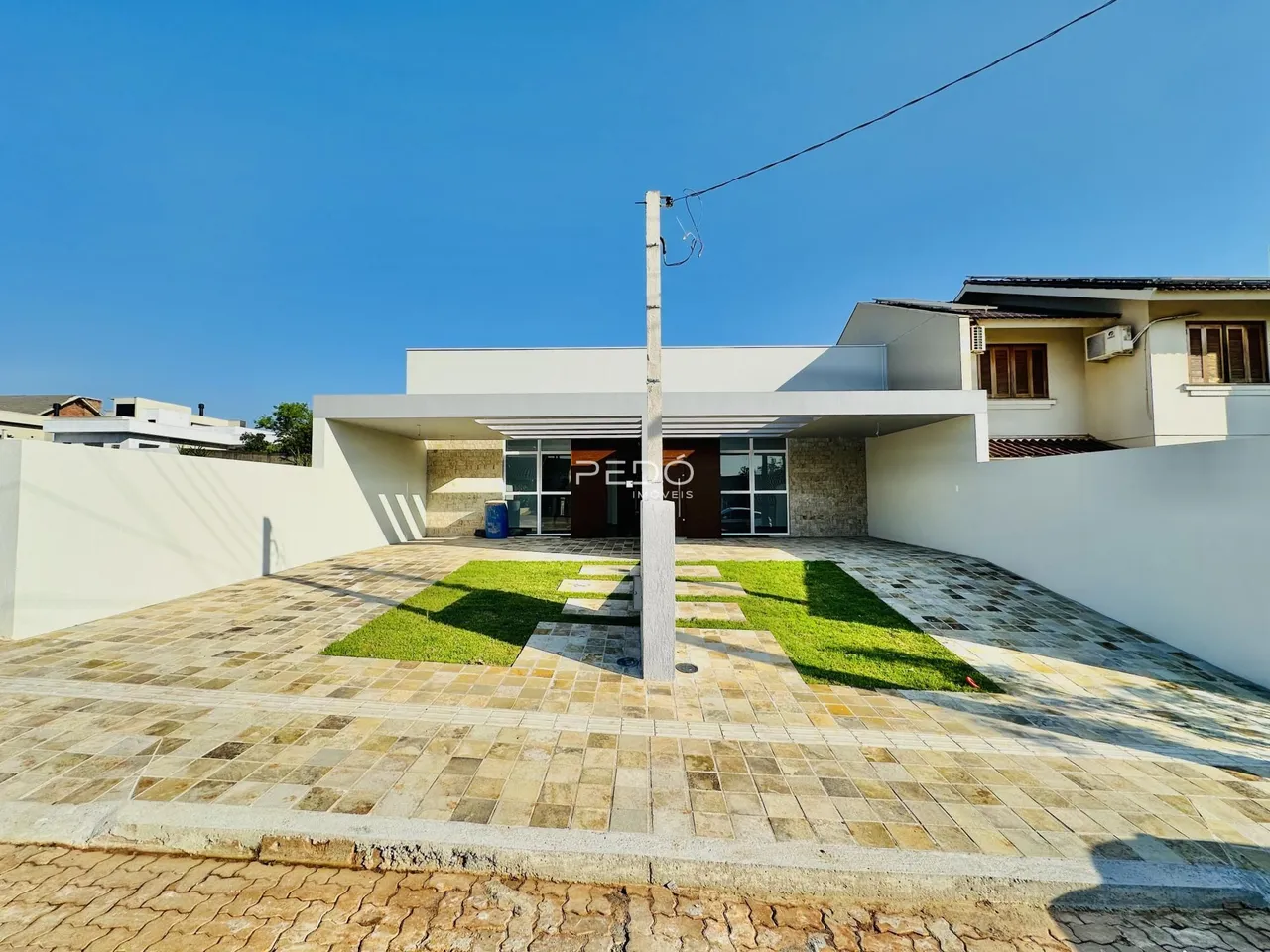 Fachada de uma residência moderna com área externa pavimentada.