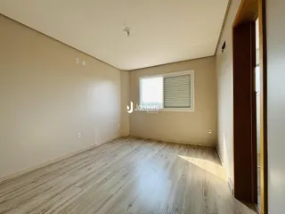 Uma sala de estar com piso de madeira clara e paredes bege.