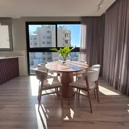 Sala de estar com piso de madeira e mesa central.