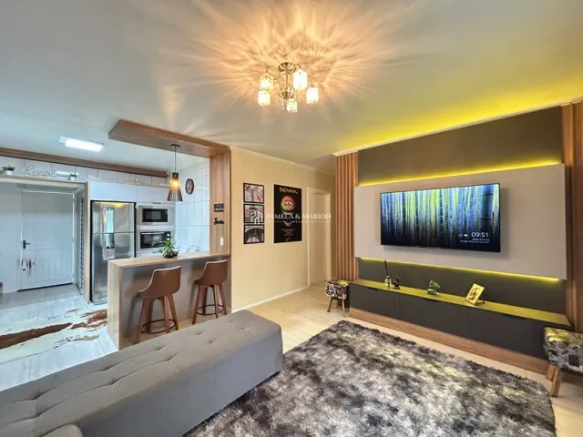 Sala de estar com sofá e painel de TV na parede em um apartamento.