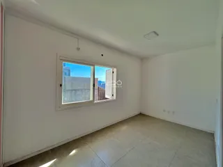 Ambiente interno de uma sala clara com piso de cerâmica e janela.