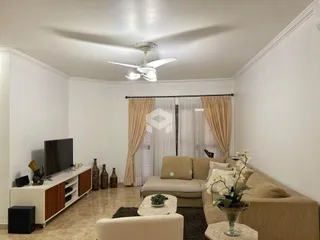 Sala de estar com sofá e televisão em ambiente claro.