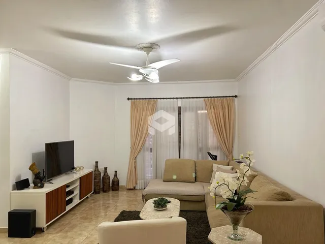 Sala de estar com sofá e televisão em ambiente claro.