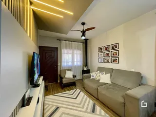 Sala de estar com sofá e televisão em ambiente claro.