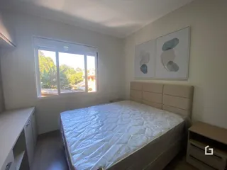 Quarto com janela e cabeceira de madeira clara.