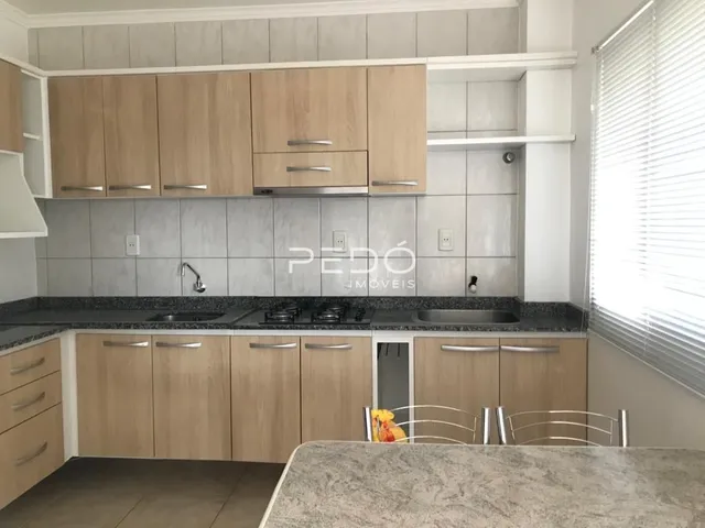 Foto de uma cozinha com armários de madeira clara e revestimento cinza.