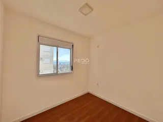 A sala apresenta piso de madeira e uma janela com vista para a paisagem.