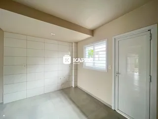 Hall de entrada com paredes brancas e piso claro.