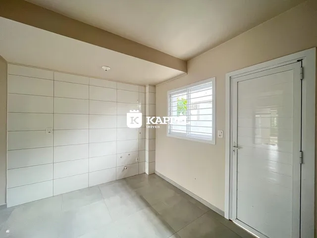 Hall de entrada com paredes brancas e piso claro.