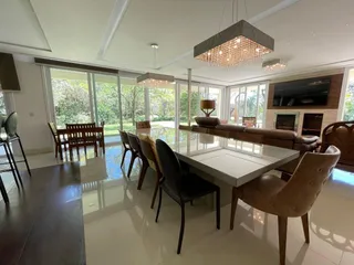 Sala de estar com grandes janelas de vidro e mesa de jantar.