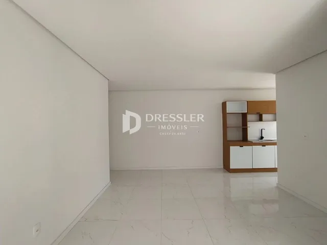 A foto mostra um corredor amplo com piso de porcelanato claro.