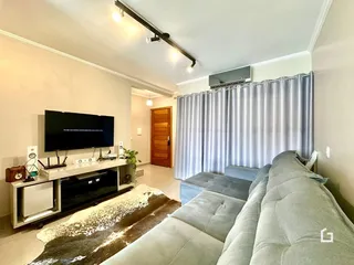 Sala de estar com sofá e televisão em um imóvel no Brasil.