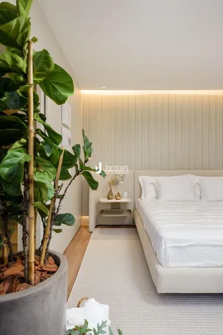 Quarto moderno com cama e plantas em um ambiente claro.