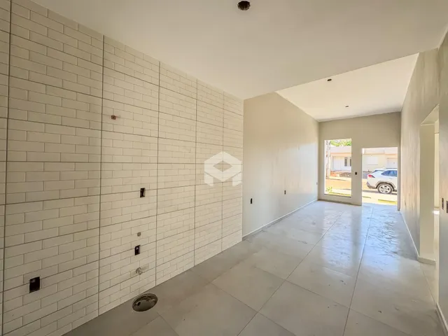 Corredor interno com parede de azulejos brancos e piso claro.
