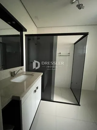 Vista parcial de uma área com bancada e divisória de vidro em um imóvel.