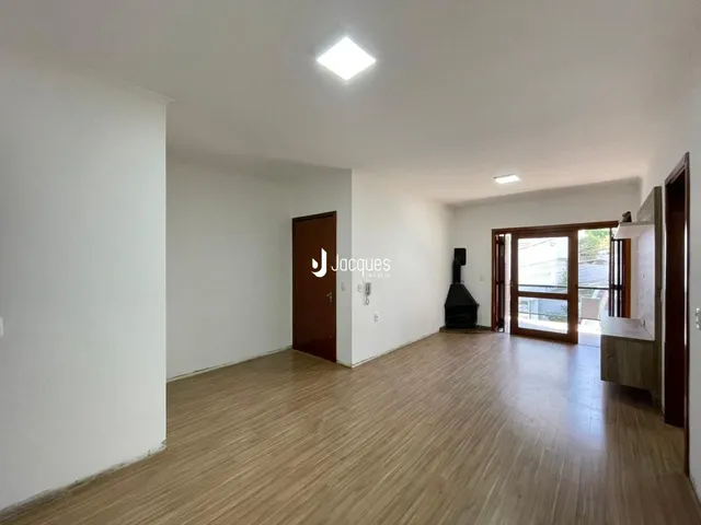 Interior de uma sala com piso de madeira clara e paredes brancas.