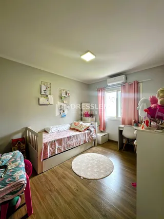 Quarto com cama e piso de madeira em uma residência.
