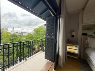 Vista de um quarto com acesso a uma varanda com vista para a paisagem verde.