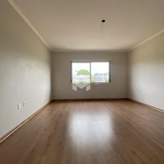 Ambiente interno de uma sala com piso de madeira clara e janela.