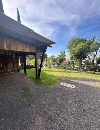 Vista externa da propriedade com gramado e estrutura de madeira.