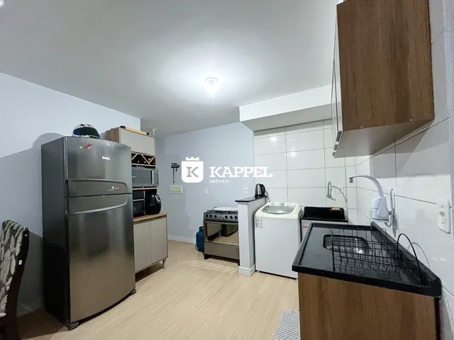 Foto interna de uma cozinha com eletrodomésticos em aço inoxidável e piso de madeira.