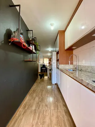 Vista de um corredor com piso de madeira e armários brancos em uma residência.