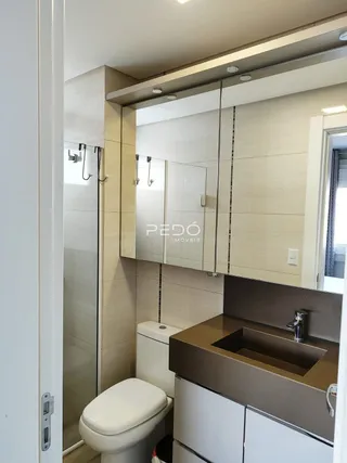 Foto de um banheiro interno com azulejos claros e louças sanitárias brancas.