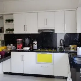Foto da cozinha com armários brancos e bancada escura.