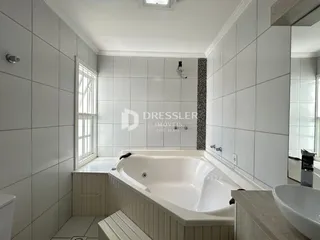 Foto de um banheiro com banheira e revestimento cerâmico branco.