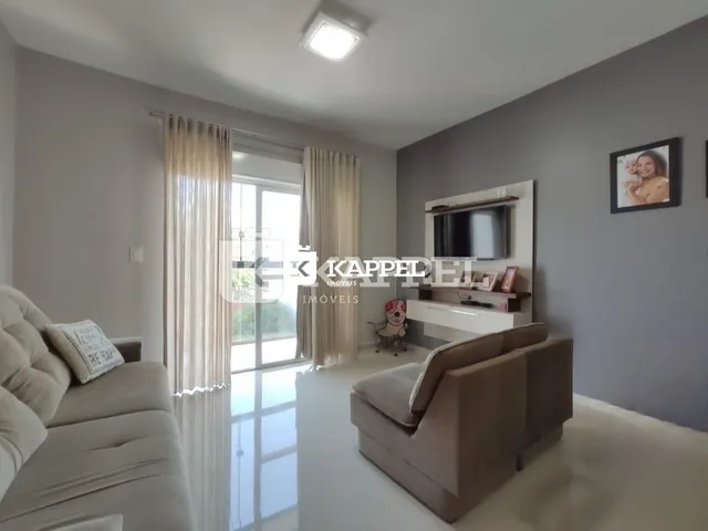 Sala de estar com sofá e janela de grande porte em um apartamento.
