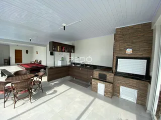 Ambiente de sala de estar com cozinha integrada e piso de cerâmica.