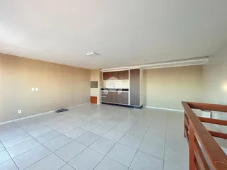 Espaço interno amplo com piso de cerâmica claro e paredes bege.