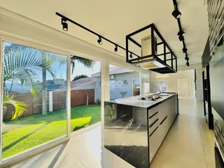 Vista da cozinha moderna com acesso a um jardim externo.