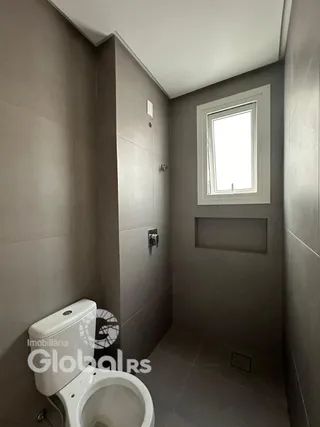Foto de um corredor interno com uma janela e um vaso sanitário.