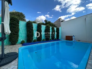 Piscina azul em um quintal com muro verde e parede branca.